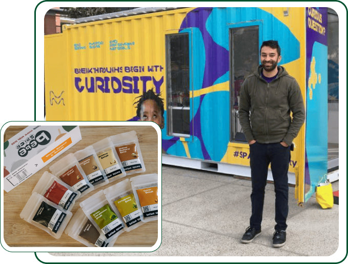 There are two images. The main one is the founder of Bebe Spice standing in front of a yellow shipping container retrofitted to be a science lab. Overlapping that image on the bottom right is a large Bebe Spice Kit surrounded by the spices contained within.